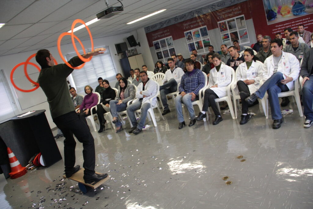 Palestra em ambiente de trabalho onde palestrante faz malabarismo com argolas.