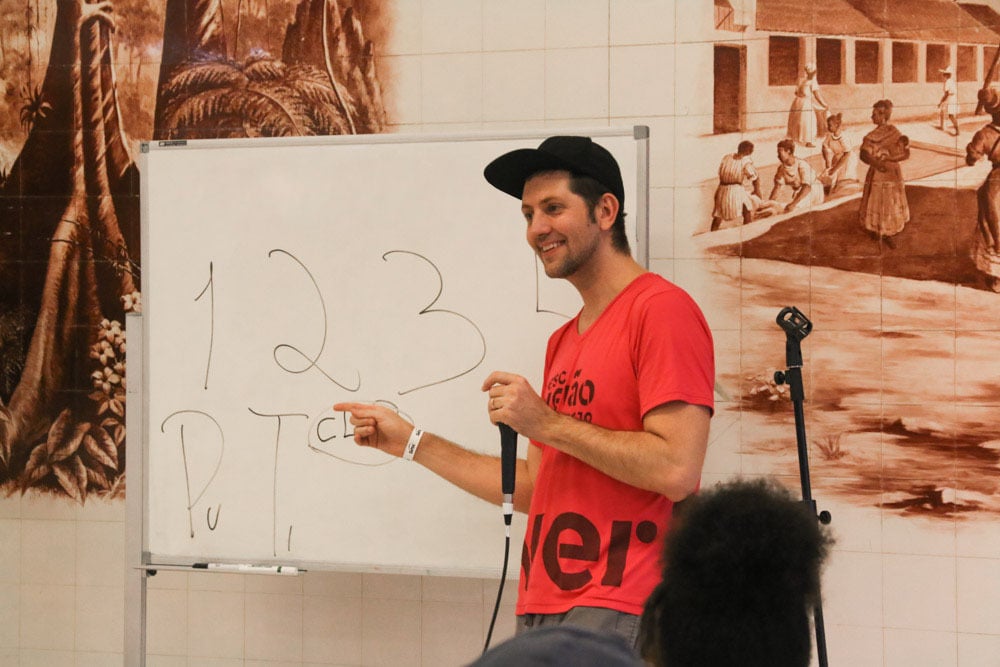 Aula de canto com professor de beatbox mostrando passo a passo em cartaz