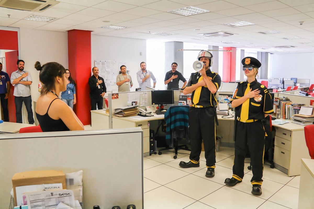 Imagem de uma sala cheia de pessoas assistindo a uma palestra com comediantes
