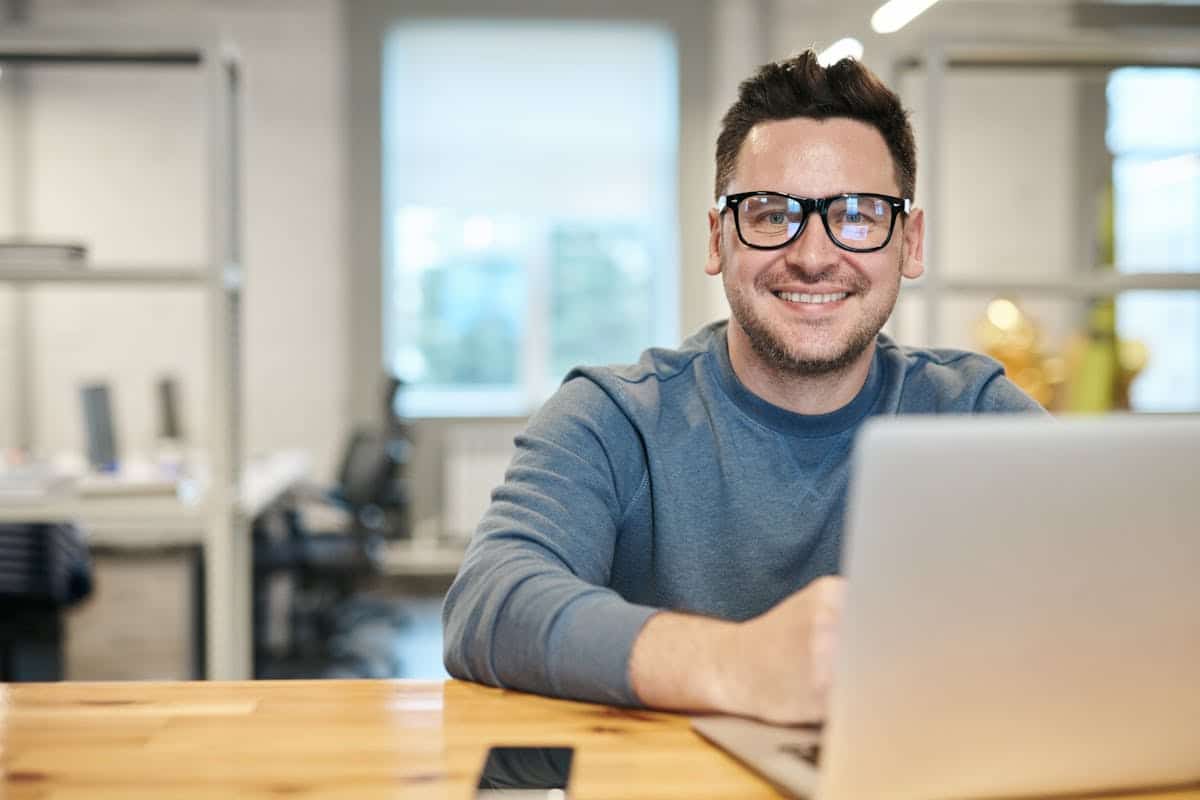 Homem de frente para laptop, sorrindo