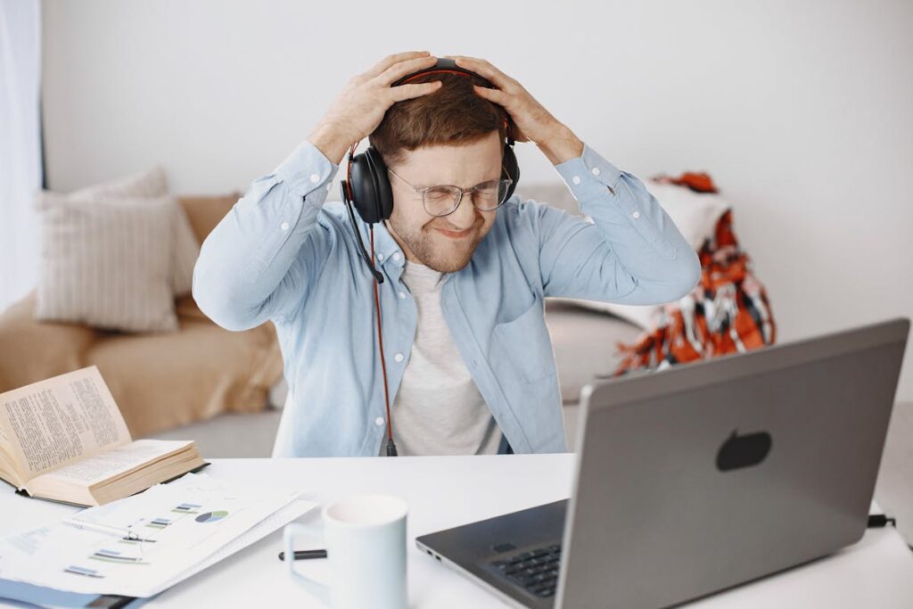 Homem preocupado, com a mão na cabeça, de frente para seu computador
