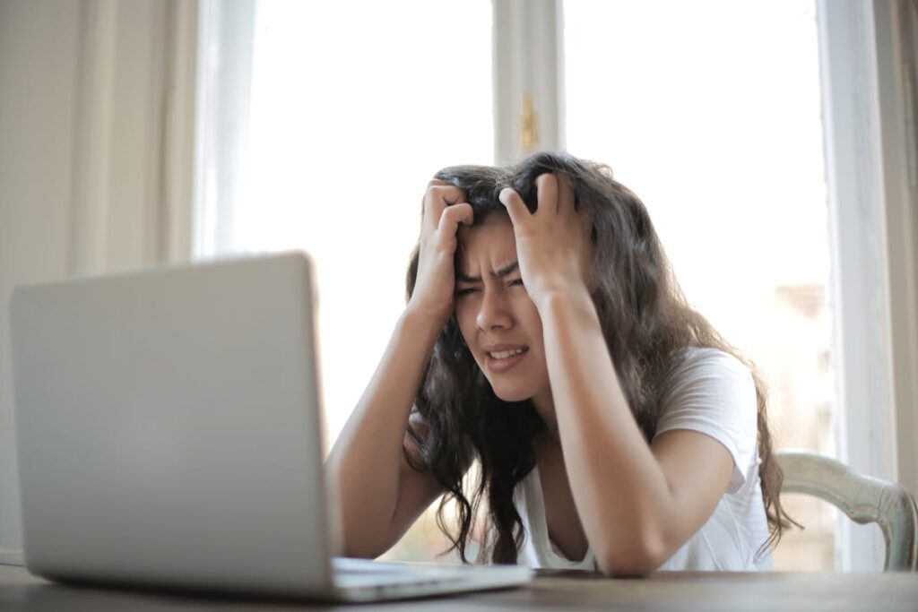 Mulher de frente para o computador, com a mão na cabeça
