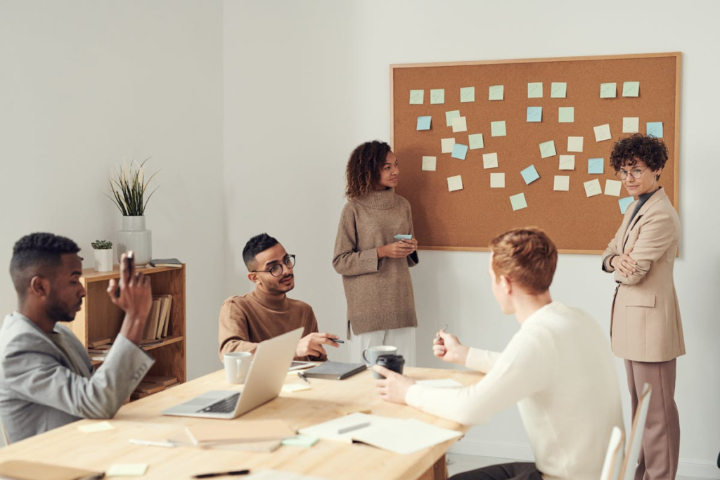 Equipe em ambiente de trabalho, analisando quadro com post-its.