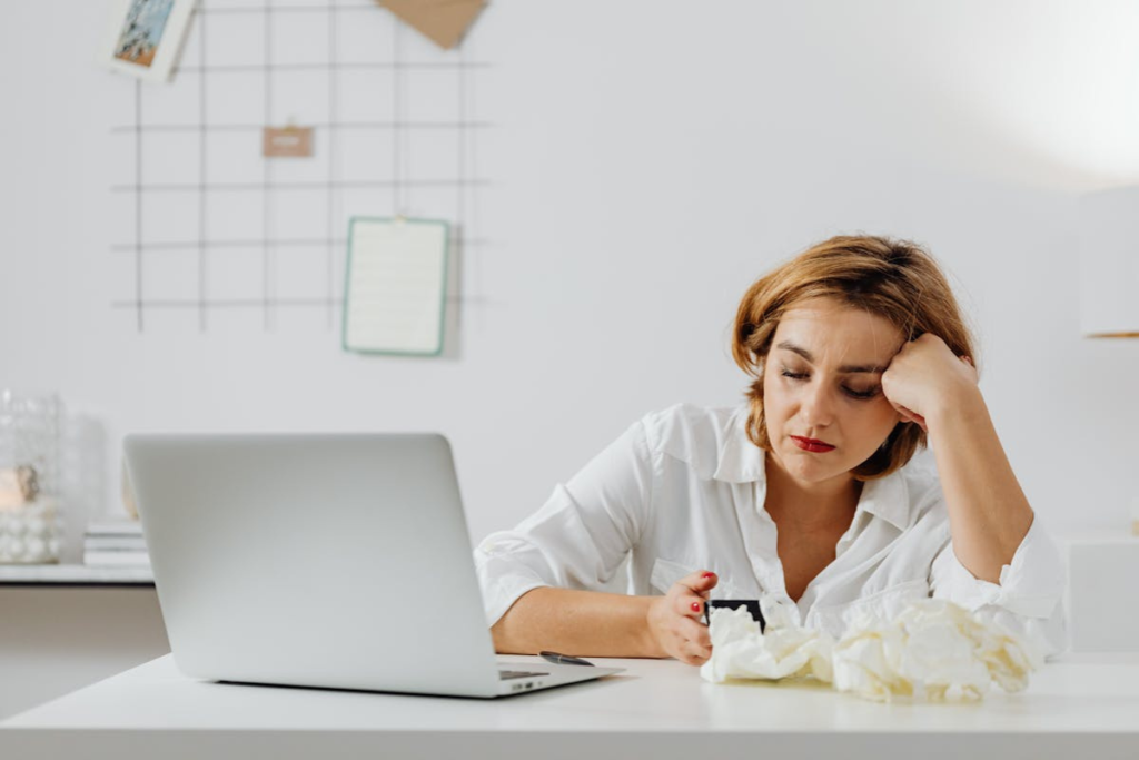 Mulher de frente para o laptop, com aspecto cansado.
