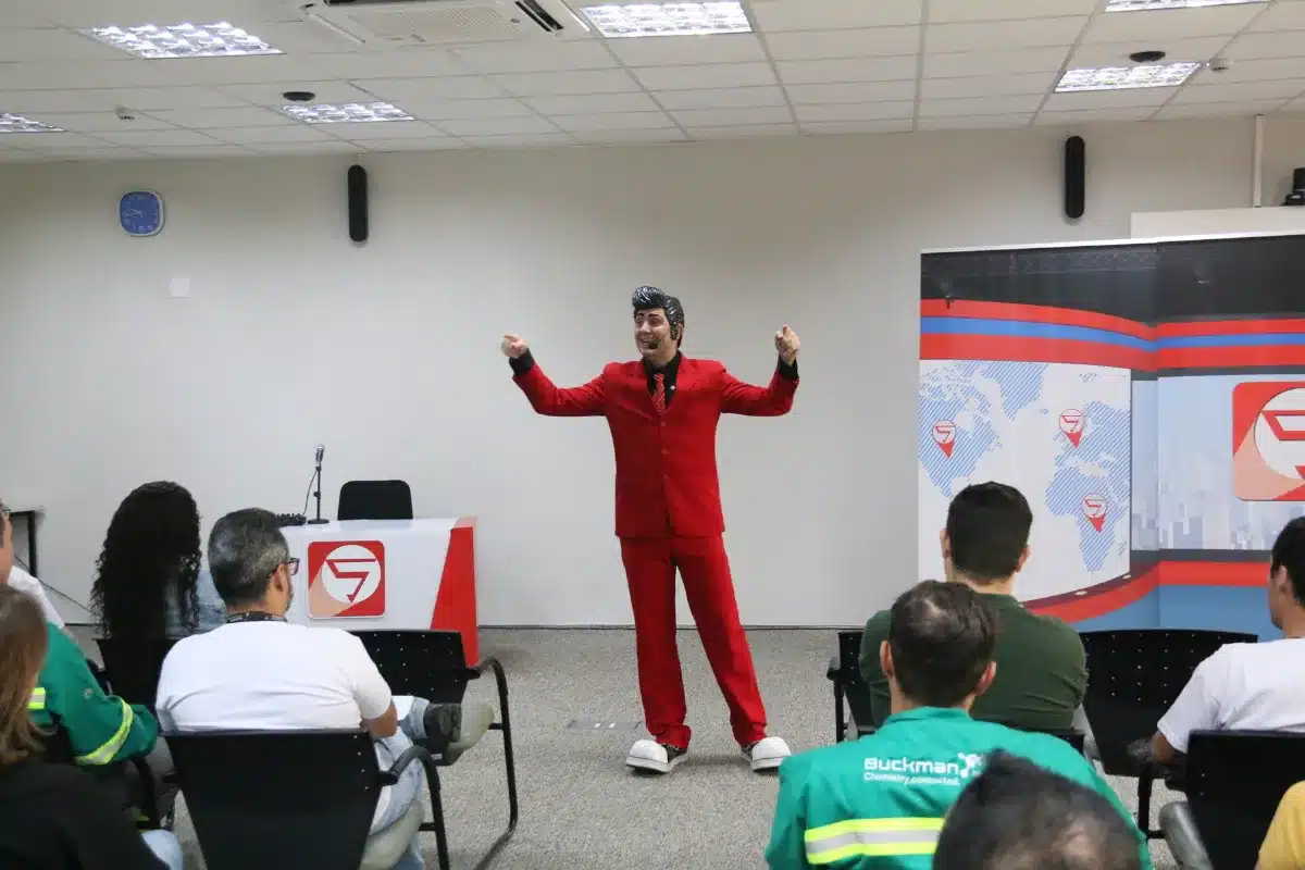 Palestrante de roupa vermelha falando sobre saúde mental para colaboradores em sala corporativa