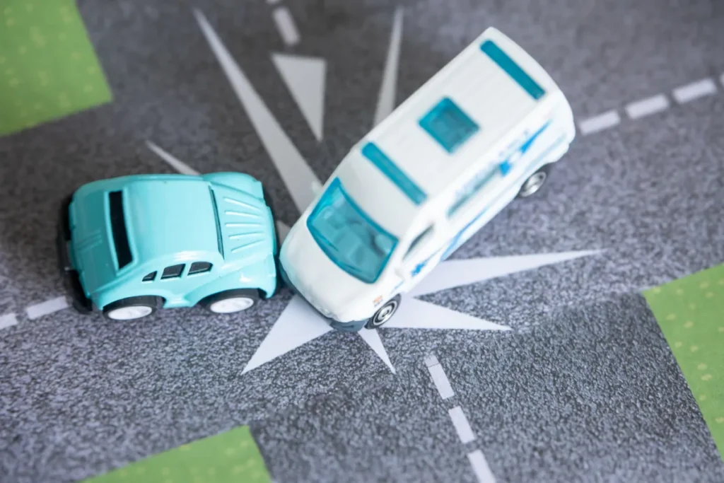 dois carrinhos em miniatura colidindo em um cruzamento representado em uma pista de brinquedo