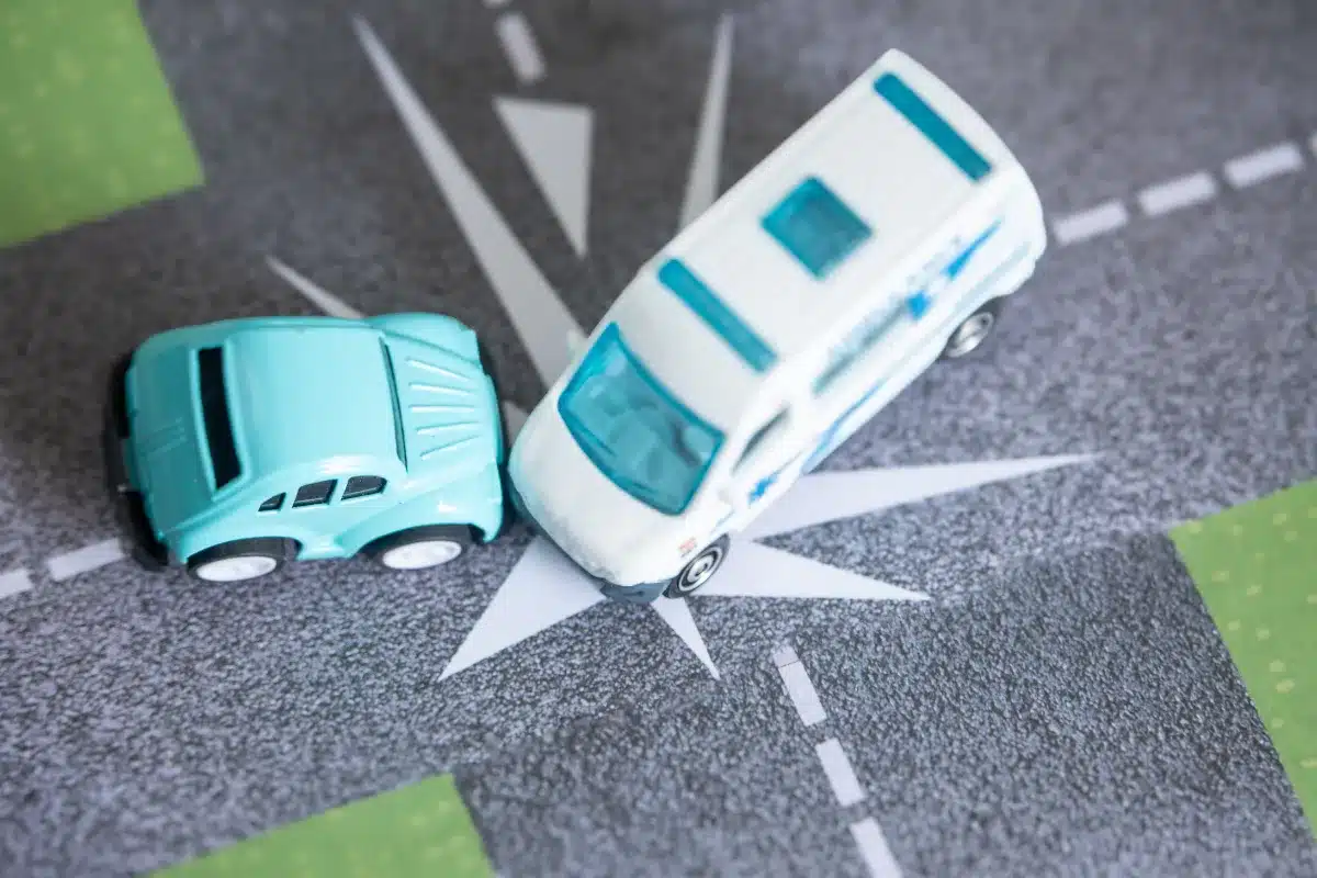 dois carrinhos em miniatura colidindo em um cruzamento representado em uma pista de brinquedo