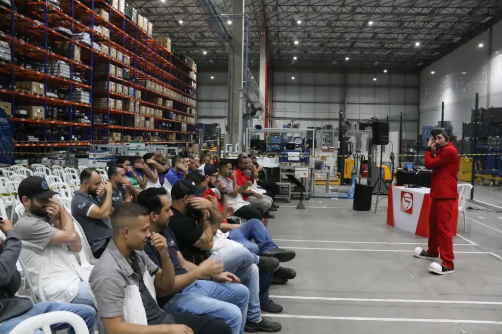 Colaboradores participando de atividade interativa durante evento de segurança do trabalho em galpão industrial.