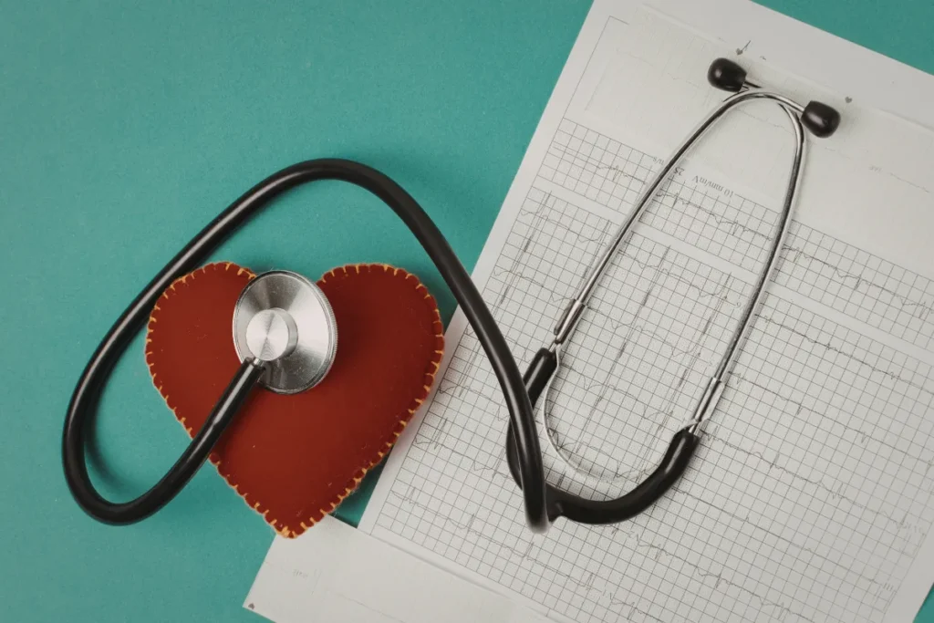 Estetoscópio sobre um gráfico médico ao lado de um objeto em formato de coração em fundo verde.