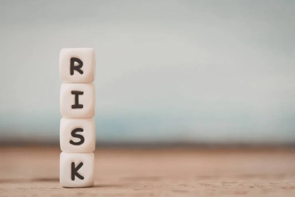 Cubos empilhados formando a palavra risk sobre uma superfície de madeira com fundo neutro desfocado