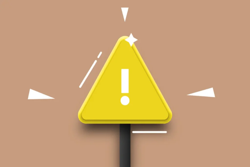 Placa triangular amarela com símbolo de exclamação representando alerta de risco sobre fundo simples
