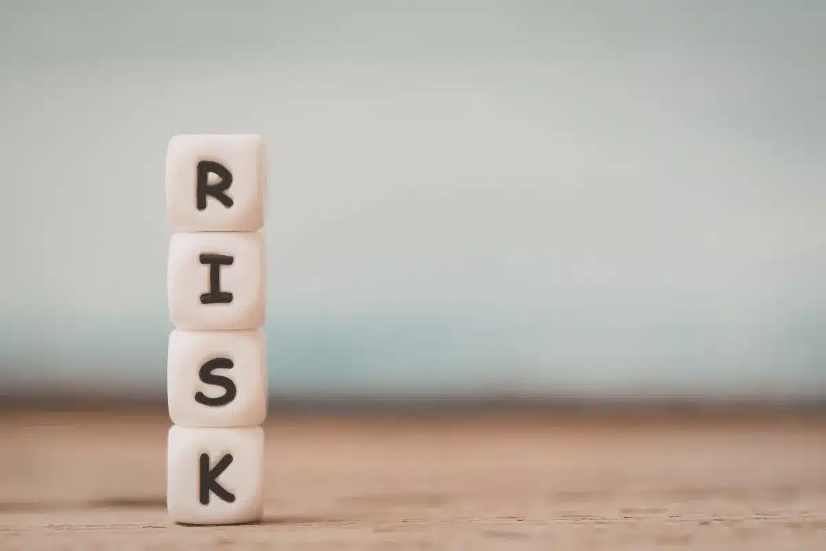 Cubos empilhados formando a palavra risk sobre uma superfície de madeira com fundo neutro desfocado