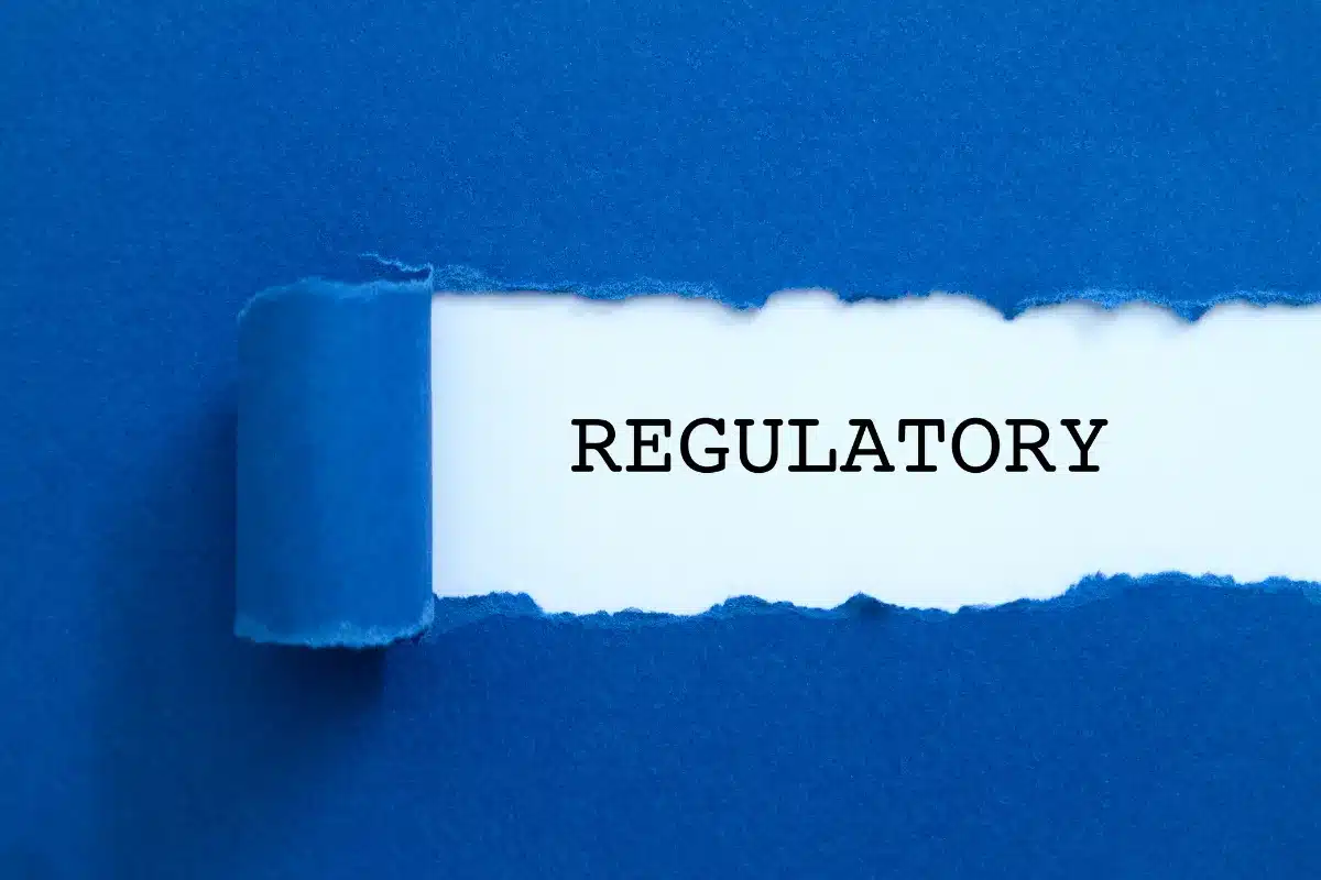 papel rasgado revelando a palavra regulatory em fundo azul