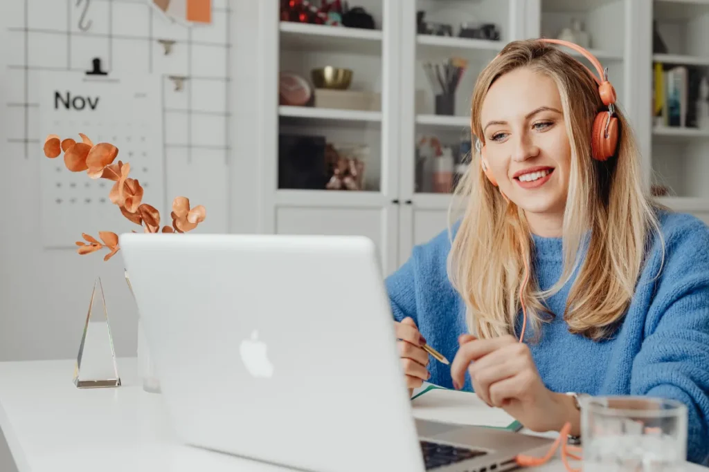 Colaboradora usando fones e notebook em casa durante atividade de SIPAT online para empresas.