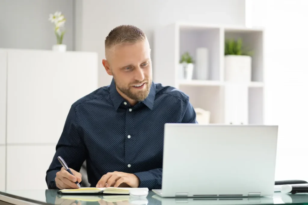 Profissional organizando conteúdo da SIPAT online para empresas com notebook e anotações de planejamento