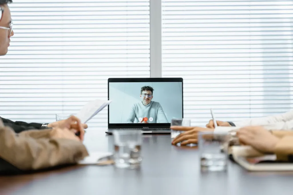 Equipe reunida em sala acompanhando SIPAT online com palestrante remoto em tela durante encontro corporativo.