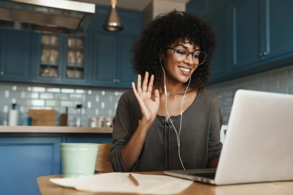 Colaboradora em home office participa de SIPAT EAD pelo notebook usando fones durante treinamento remoto corporativo.