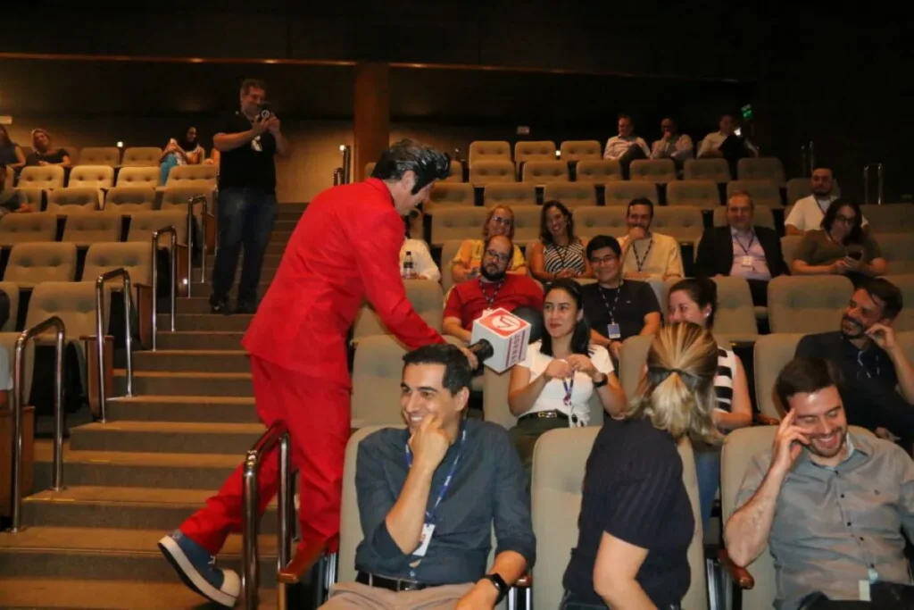 Apresentador interagindo com colaboradores durante SIPAT para empresa em auditório corporativo com alto engajamento.