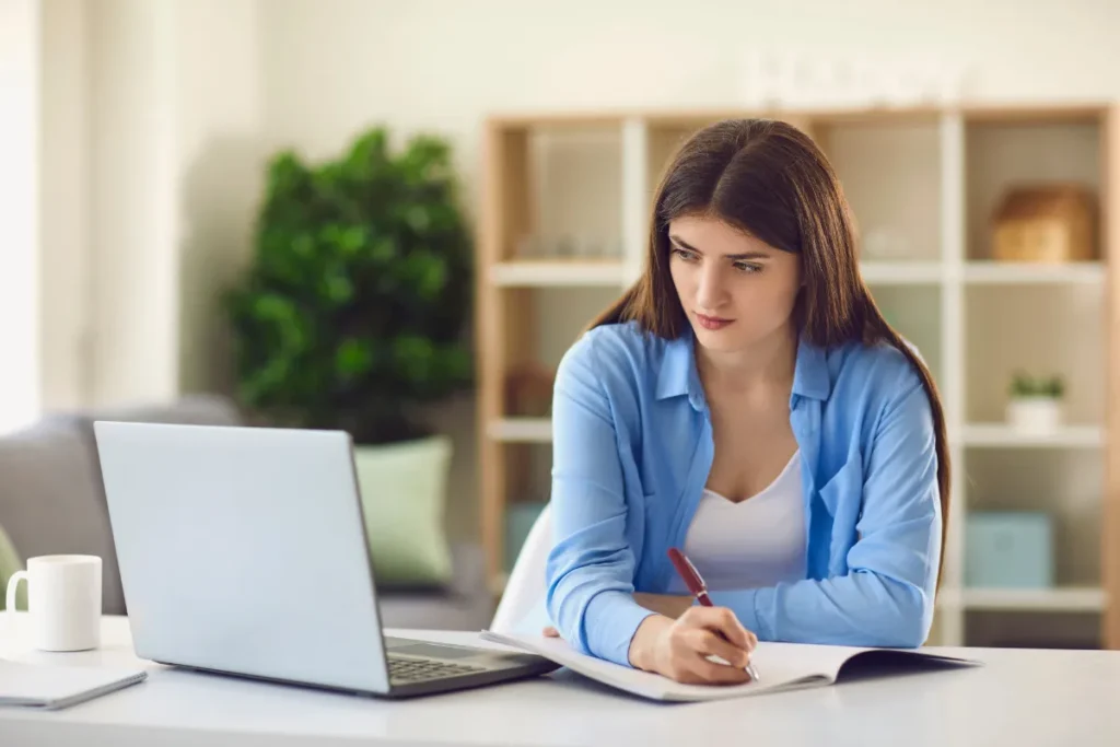 Colaboradora participando de treinamento online com notebook e anotações durante SIPAT remota para empresas.