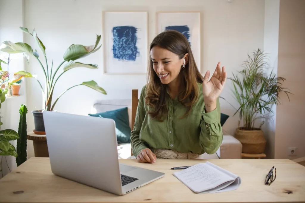 Funcionária participa de SIPAT remota pelo computador com anotações na mesa durante ação digital de segurança corporativa.