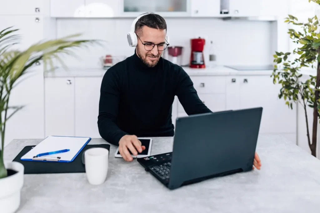Colaborador utilizando notebook e fones de ouvido para acompanhar atividades de SIPAT online em home office.