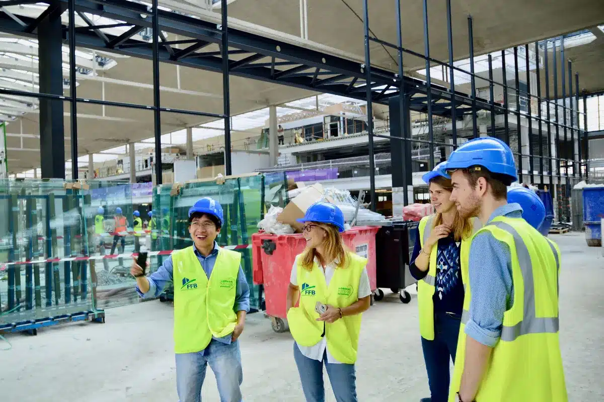 Equipe com capacetes e coletes refletivos reunida em área de construção