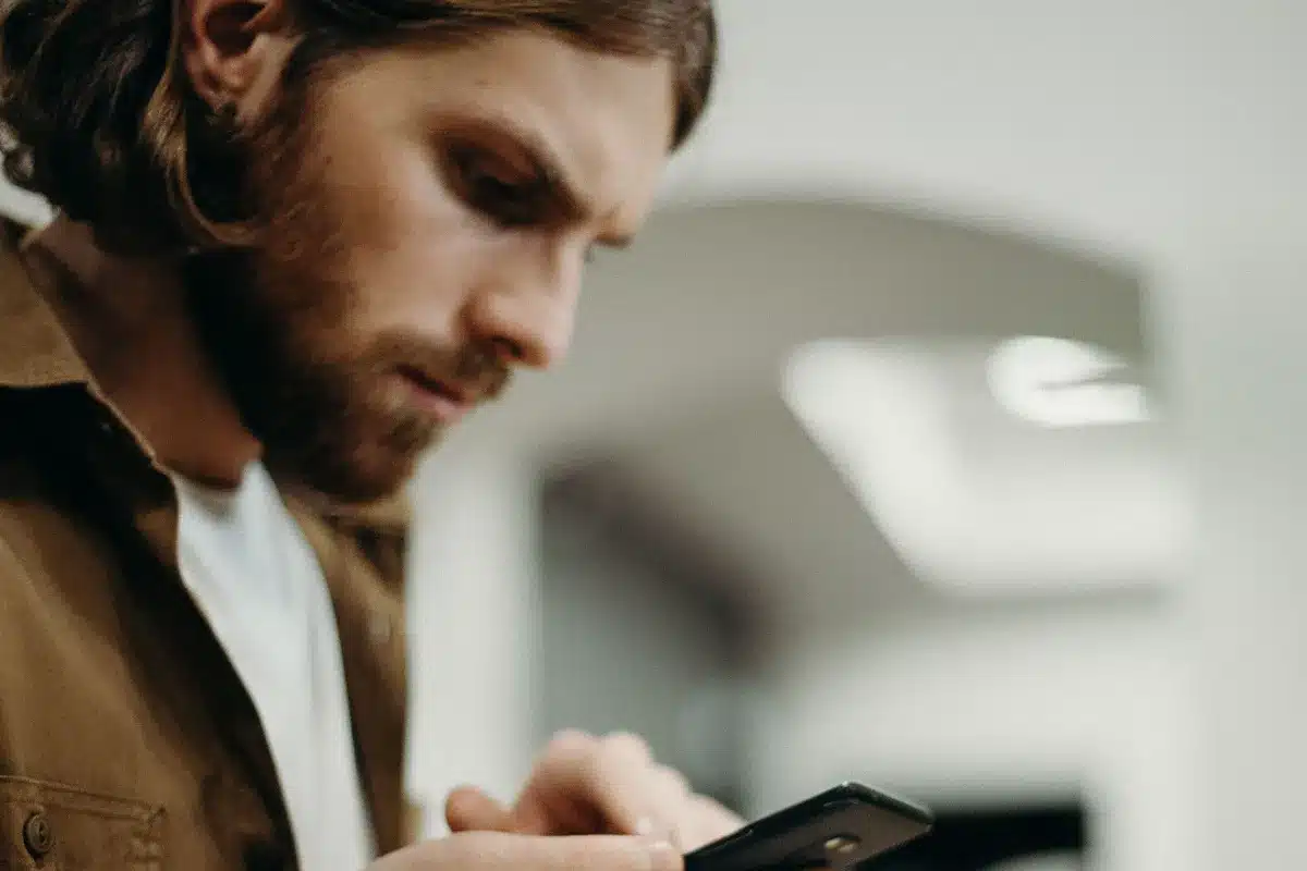 Profissional em escritório usando smartphone ao lado de um caderno aberto