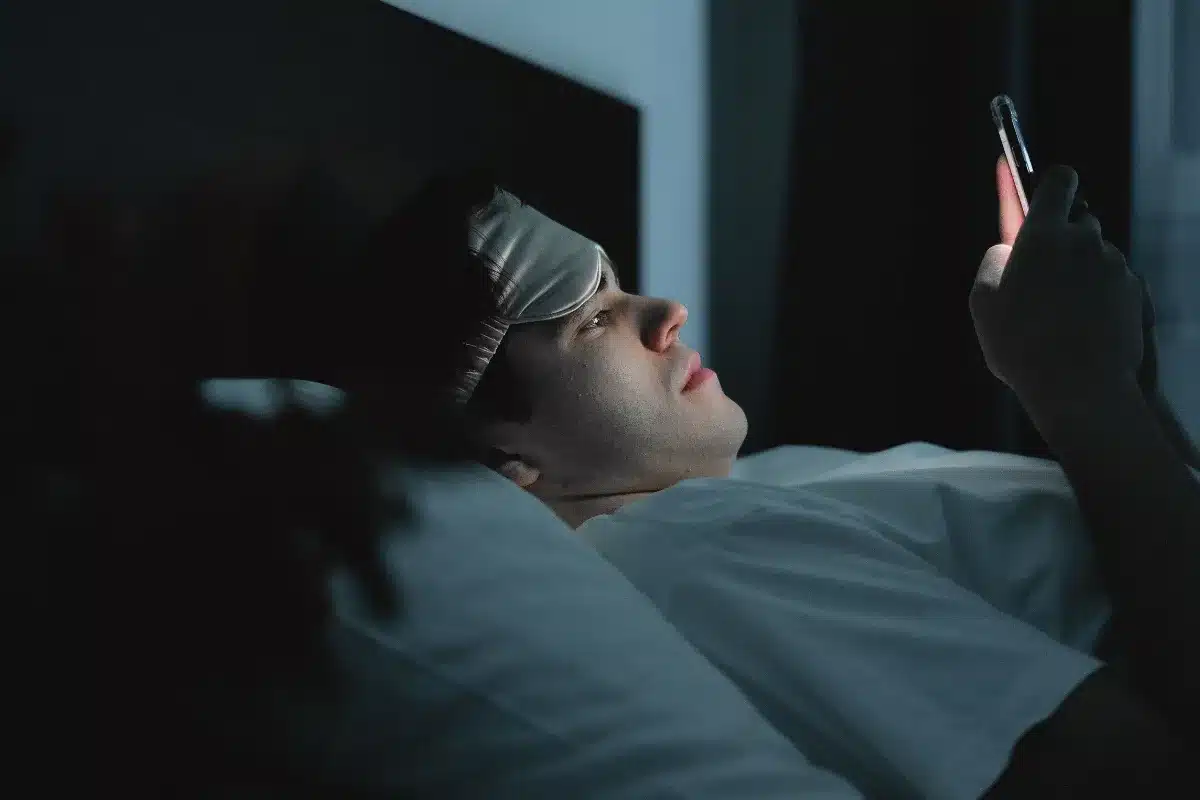 Pessoa usando smartphone na cama durante o período noturno