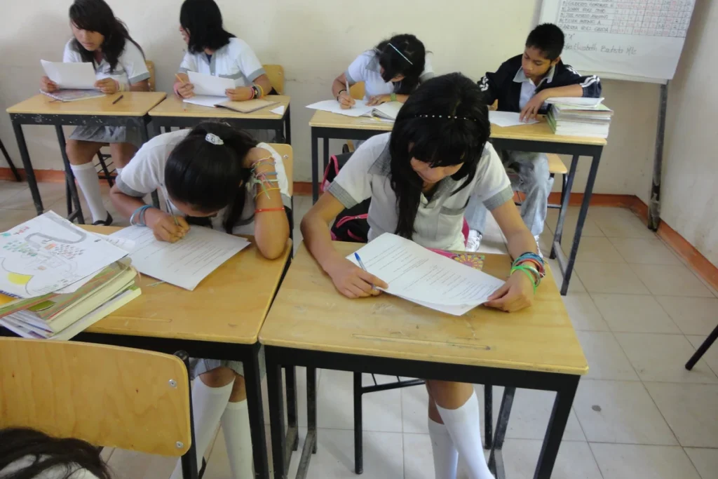 Candidato preenche informações de uma inscrição escolar em uma mesa de estudos.