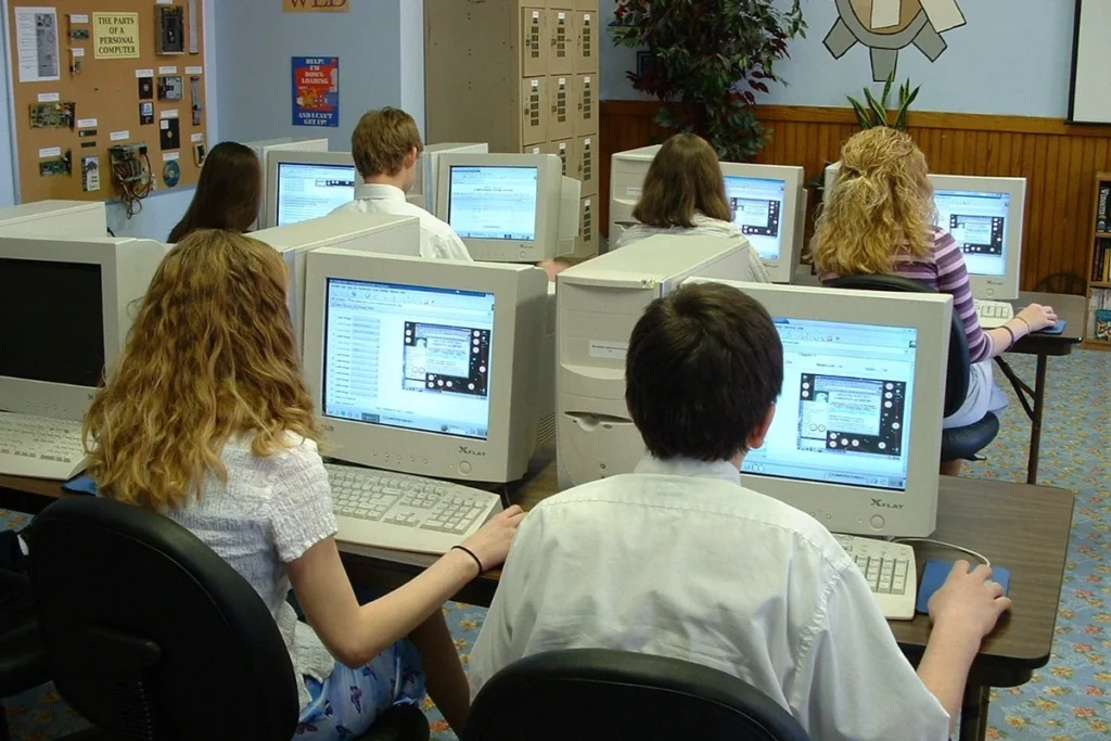 Estudantes fazem prova em computadores de uma sala de informática.