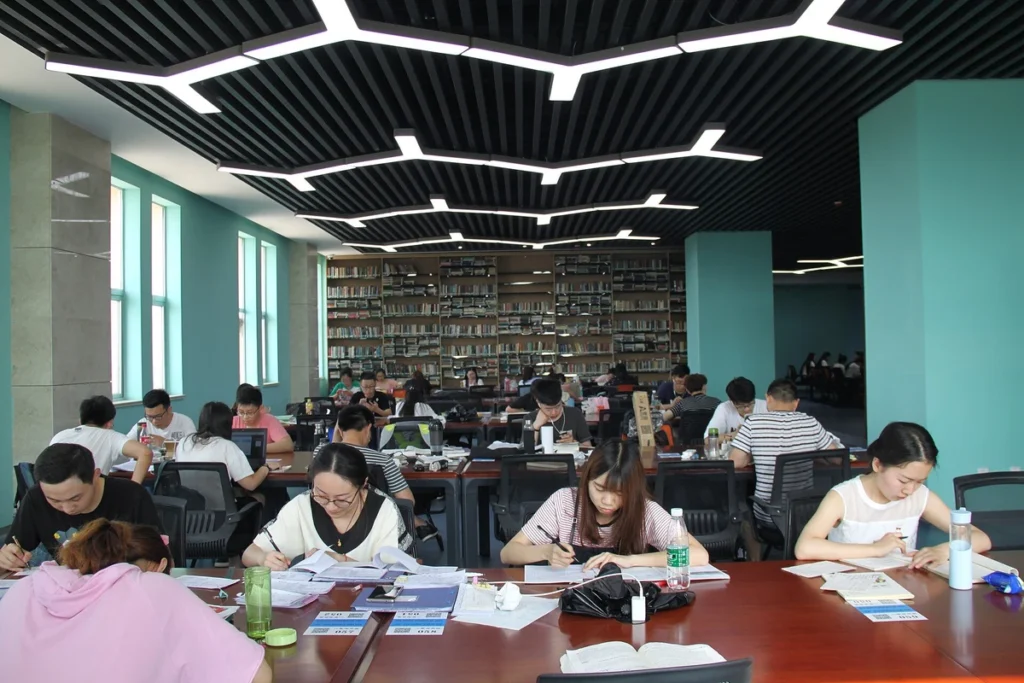 Estudantes leem e fazem anotações nas mesas de uma biblioteca.