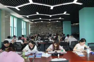 Estudantes leem e fazem anotações nas mesas de uma biblioteca.