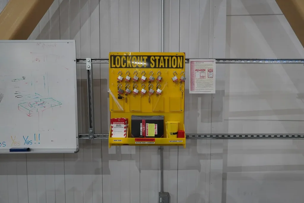 Quadro amarelo de bloqueio com cadeados e etiquetas pendurados ao lado de um quadro branco