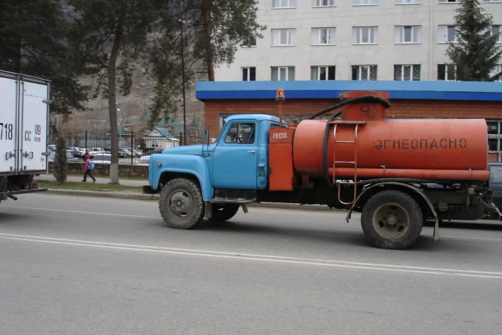 Caminhão-tanque laranja e azul de combustível parado em uma rua urbana