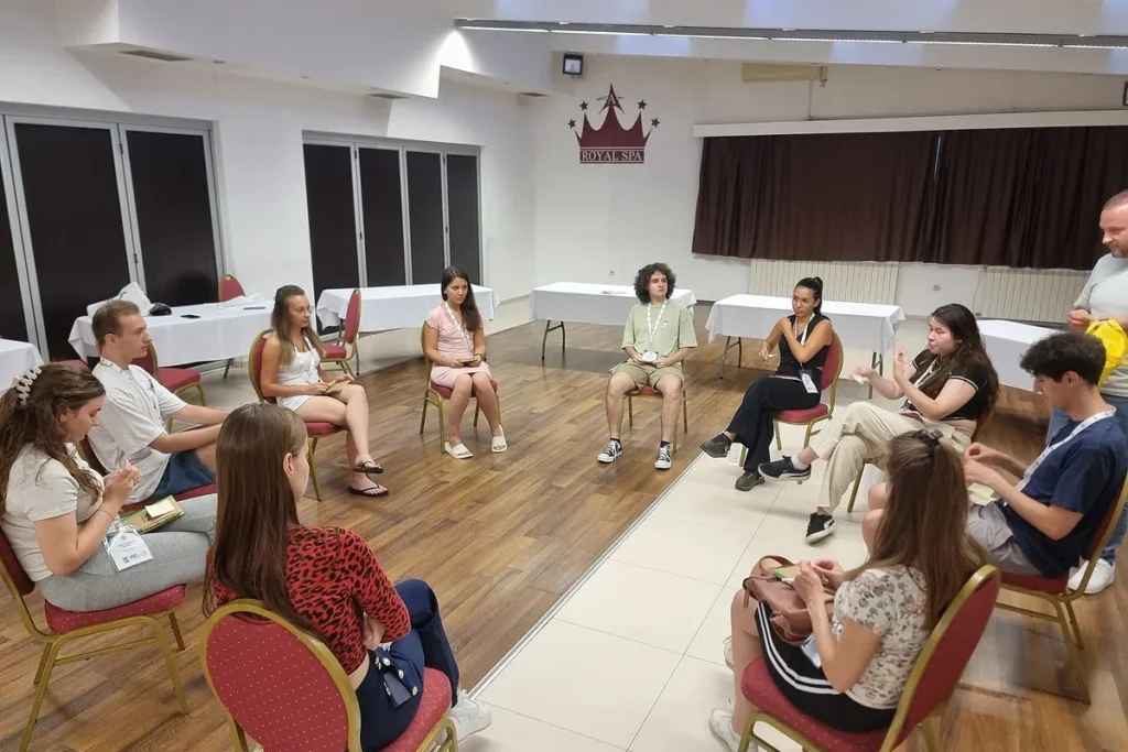 Participantes sentados em círculo numa sala durante um encontro de grupo conduzido.