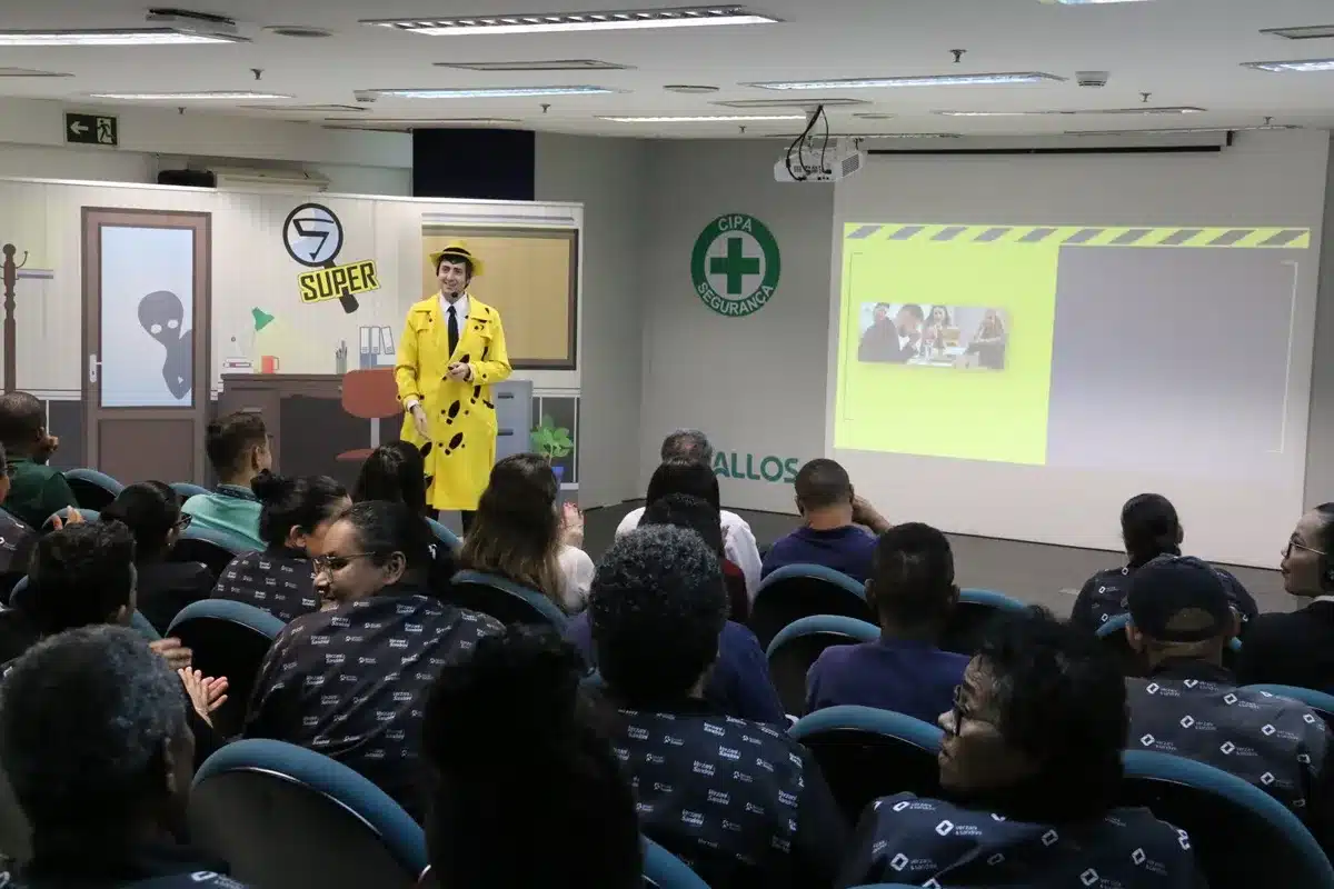Palestrante com figurino amarelo realizando treinamento de segurança do trabalho para funcionários em auditório