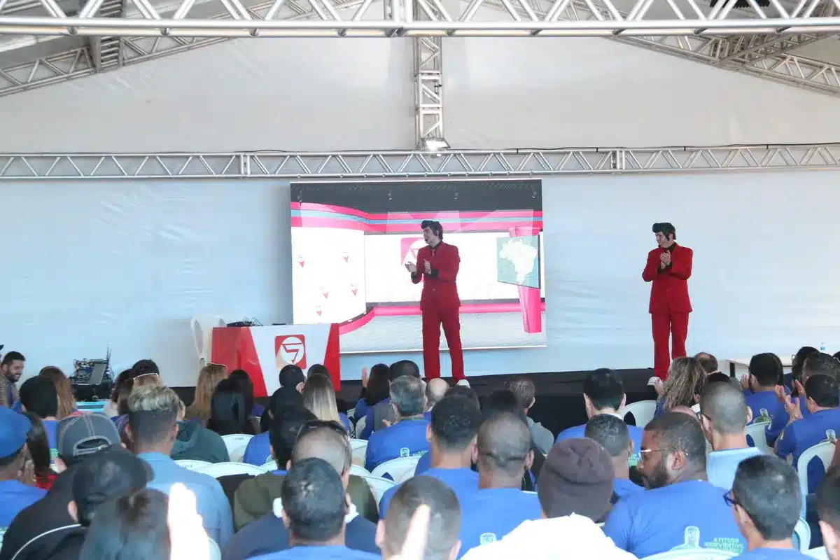 Dois palestrantes de terno vermelho falam em palco diante de um público, durante apresentação sobre apneia do sono e conscientização em saúde.