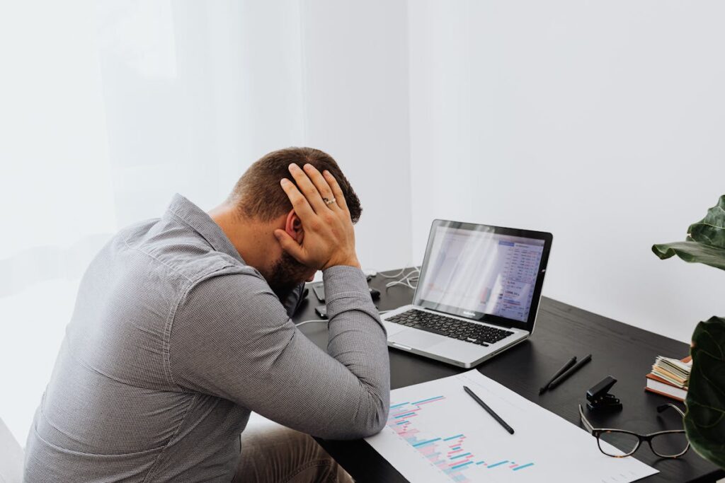 Homem de frente para um computador, com a mão na cabeça