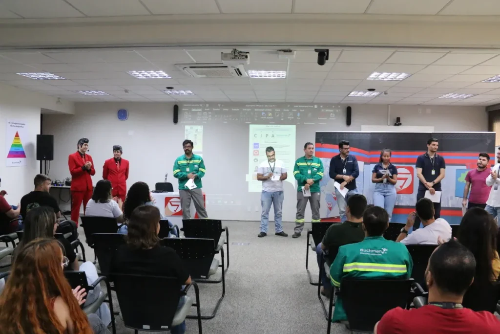 Palestrantes e profissionais em evento CIPA no palco, com slides de apresentação sobre conscientização e prevenção do câncer de próstata.