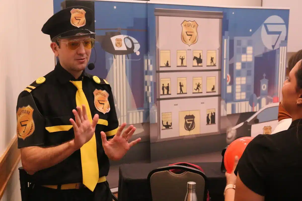 Palestrante vestido de policial conversa com participante durante ação educativa sobre sinais de trânsito