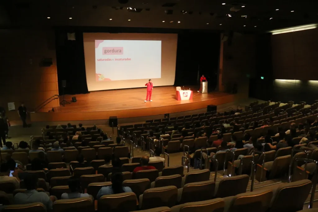 choque sépticoPalestra em um grande auditório sobre nutrição, com um slide na tela que menciona o tema "gordura" e suas variações.