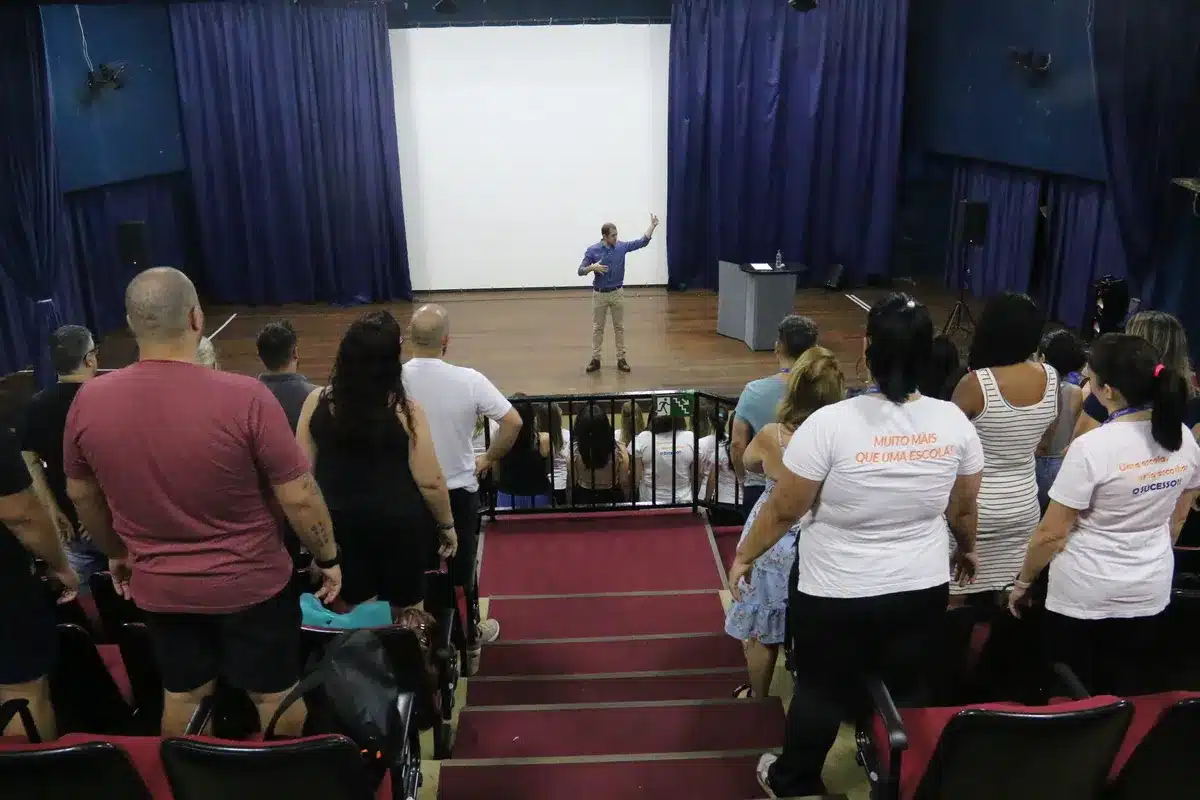 Palestrante conduz palestra em auditório sobre colesterol alto, saúde do coração e hábitos preventivos com público participando ativamente.