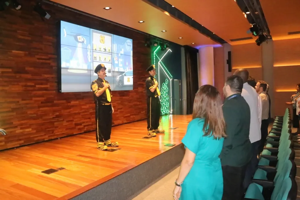 Palestrantes e público em evento corporativo com potencial para frases motivacionais engraçadas.