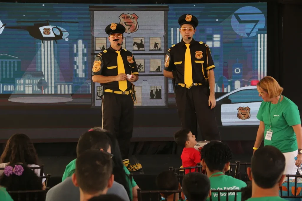 inflamação joelho, dois homens em uniformes de segurança e uma mulher em uma camiseta verde em um palco, com um grupo de pessoas assistindo a um evento.