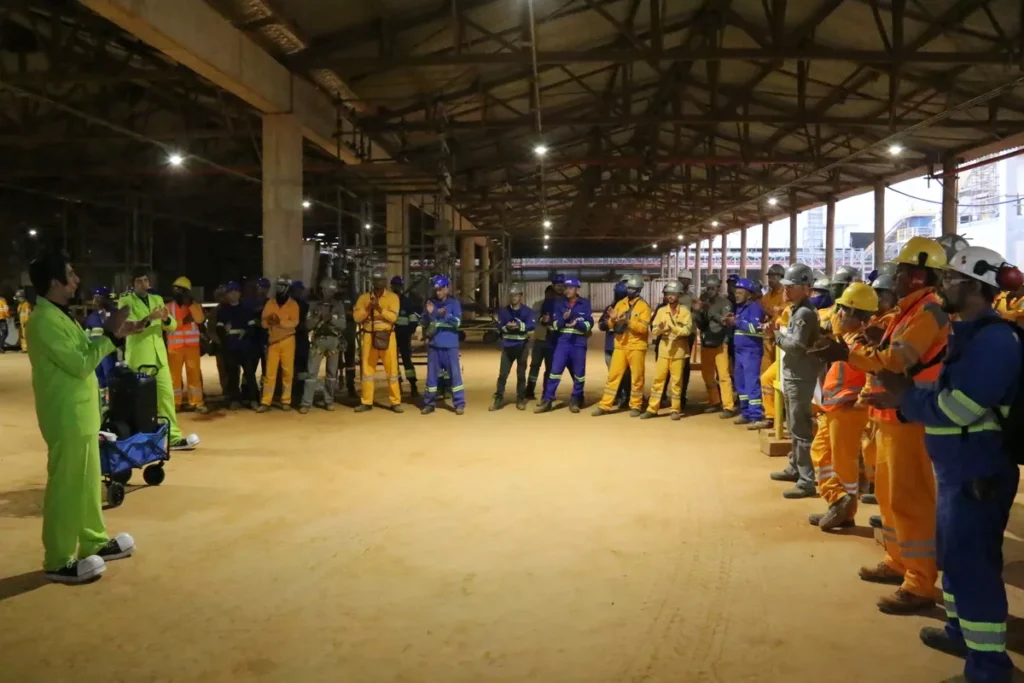 influenza, um grupo de trabalhadores em um canteiro de obras, aplaudindo um homem de terno verde-limão.