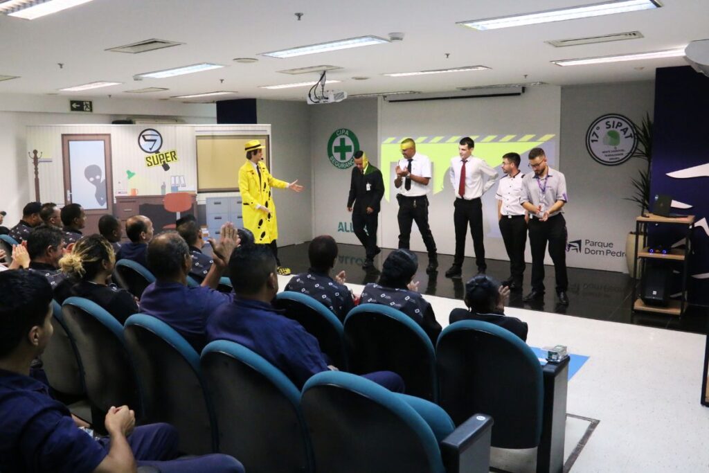 Palestrante caracterizado interagindo com colaboradores durante dinâmica em evento de SIPAT corporativa.