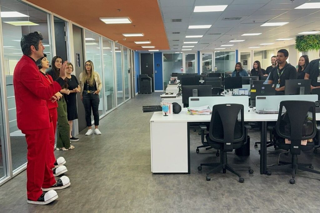 Palestrantes caracterizados conduzindo apresentação para colaboradores em escritório durante ação corporativa de SIPAT.