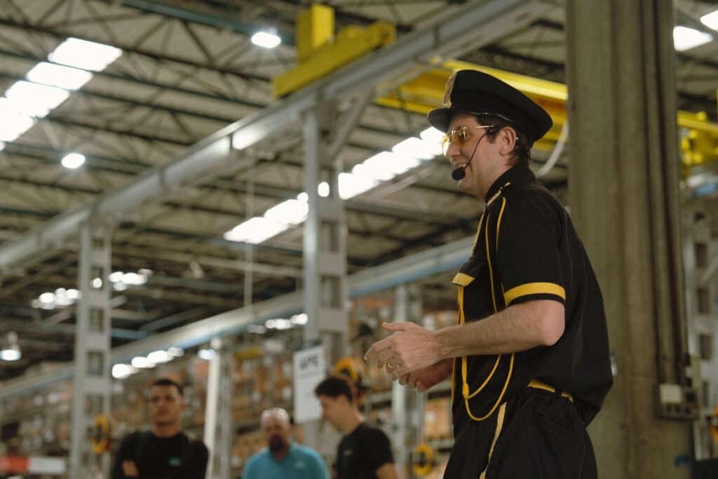 Palestrante com microfone headset conduzindo apresentação em ambiente industrial durante SIPAT.