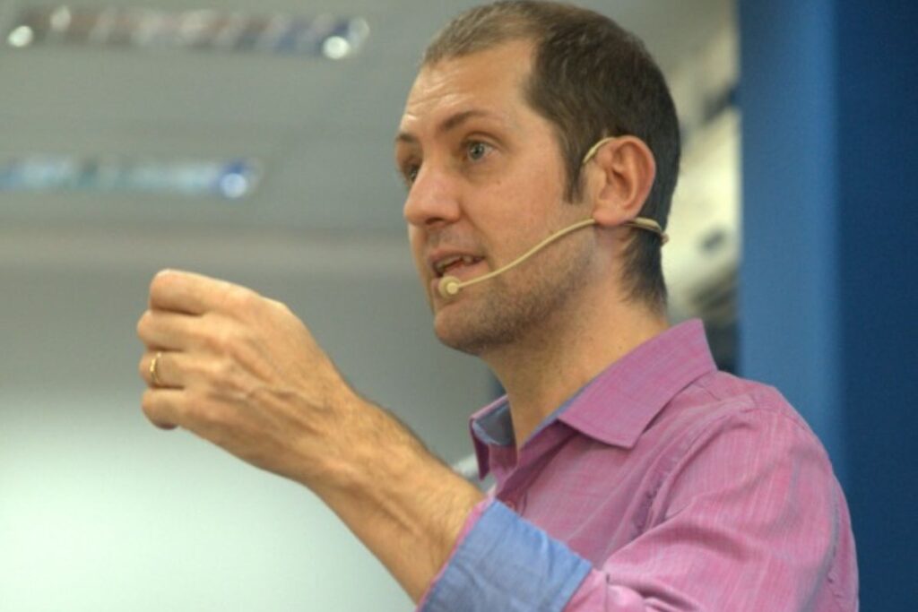 Homem realizando palestra com microfone headset em evento corporativo de treinamento profissional
