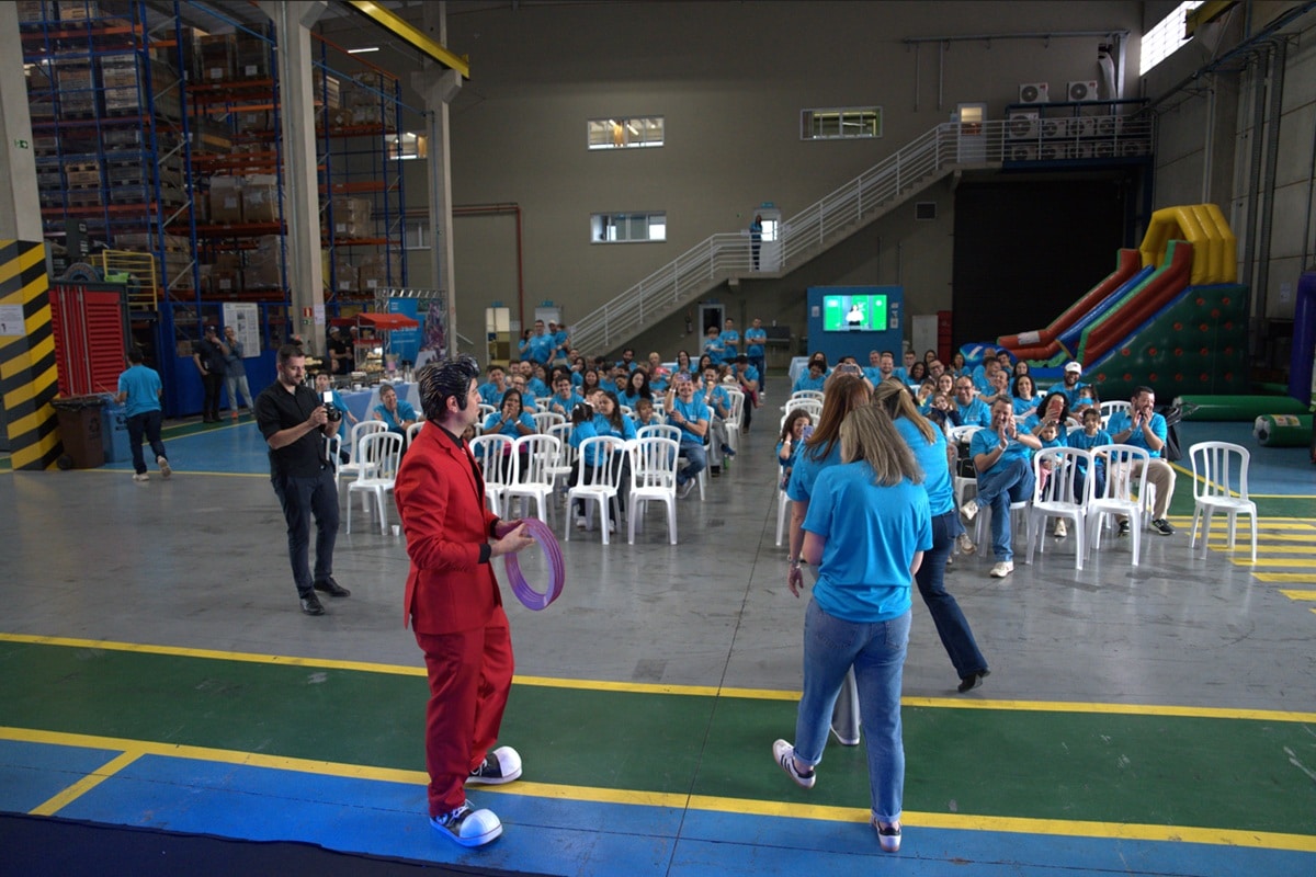 Palestrante conduzindo atividade interativa com colaboradores em galpão industrial durante treinamento